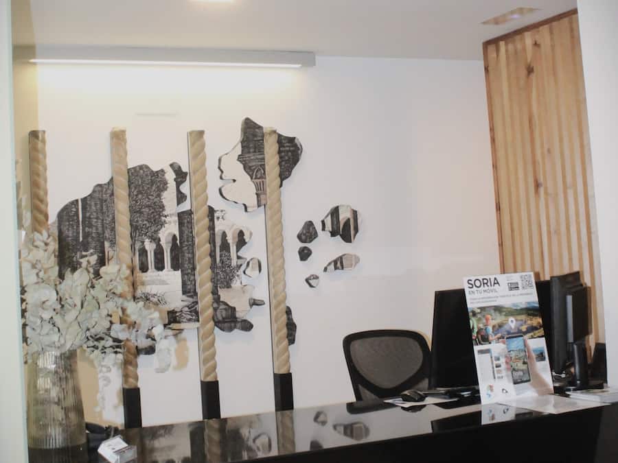 Uma mesa de recepção com design moderno, com tampo de vidro e painel de madeira à direita.