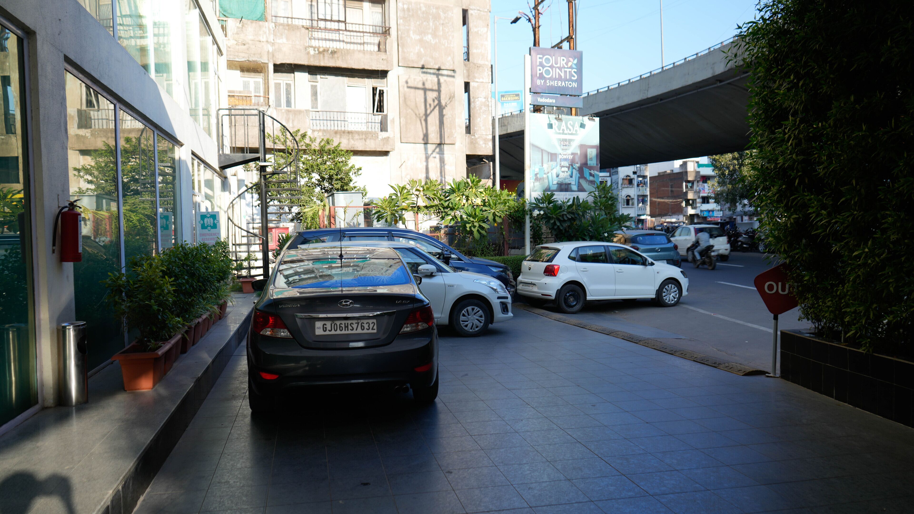 A street view with parked cars, a fire extinguisher, and a sign for 'Four Points by Sheraton'.