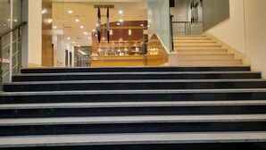 Un interior moderno con una escalera central que lleva a niveles superiores, barandillas de cristal e iluminación empotrada.