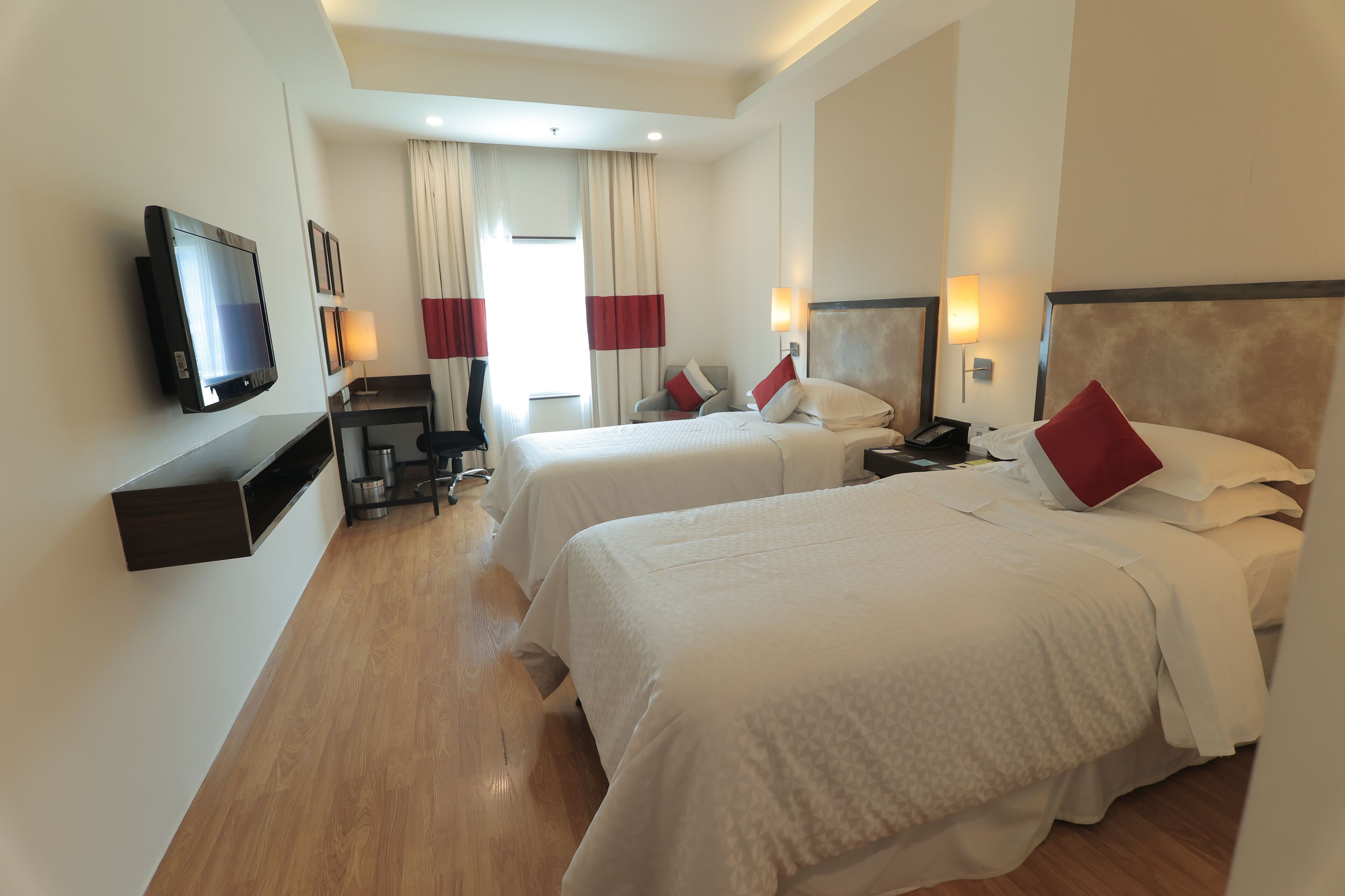 Habitación de hotel con dos camas, un televisor, un escritorio y una silla.