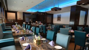 Un restaurante con varias mesas y sillas, cada conjunto con platos, vasos y servilletas.