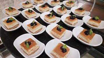 Una presentación de pequeños cuadrados de postre sobre platos blancos, dispuestos en un soporte giratorio.