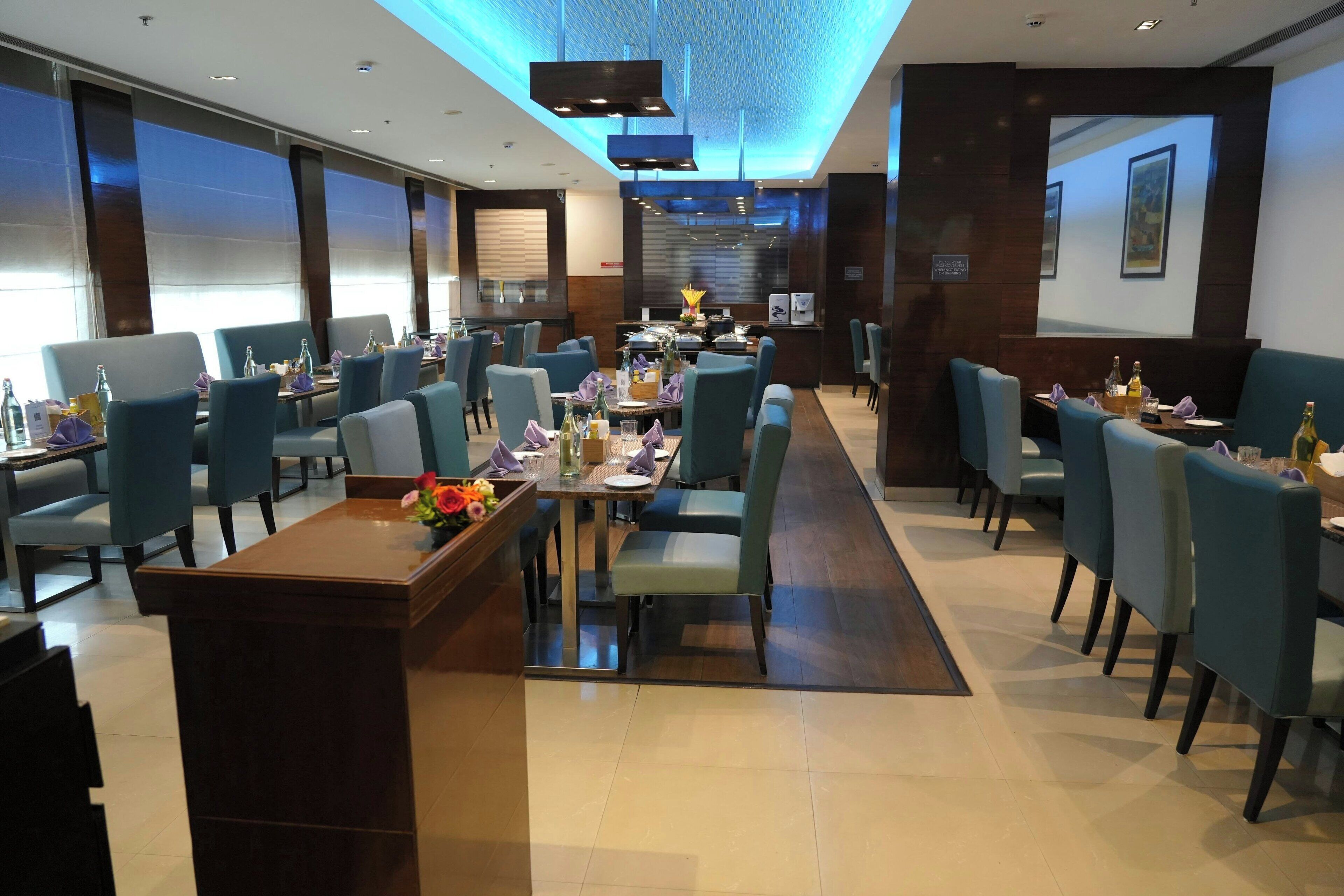 Un restaurante moderno con sillas azules, una mesa de comedor central y un jarrón decorativo.