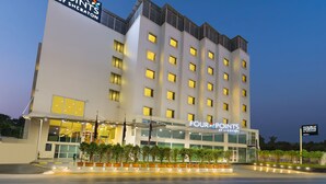 Un hotel de varios pisos con un cartel destacado que dice "FOUR POINTS BY SHERATON".