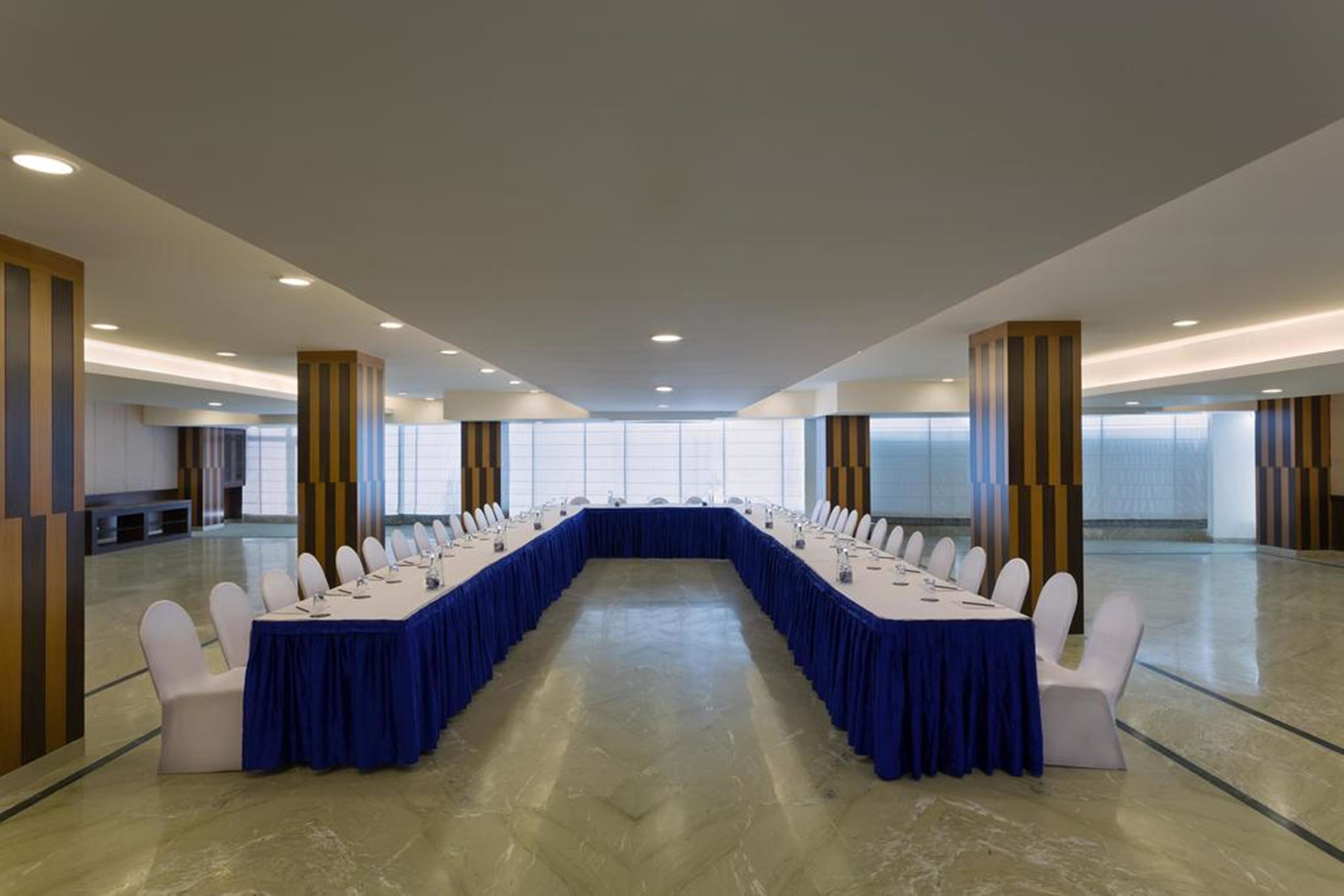 A conference room with a long table, white chairs, and a blue tablecloth.