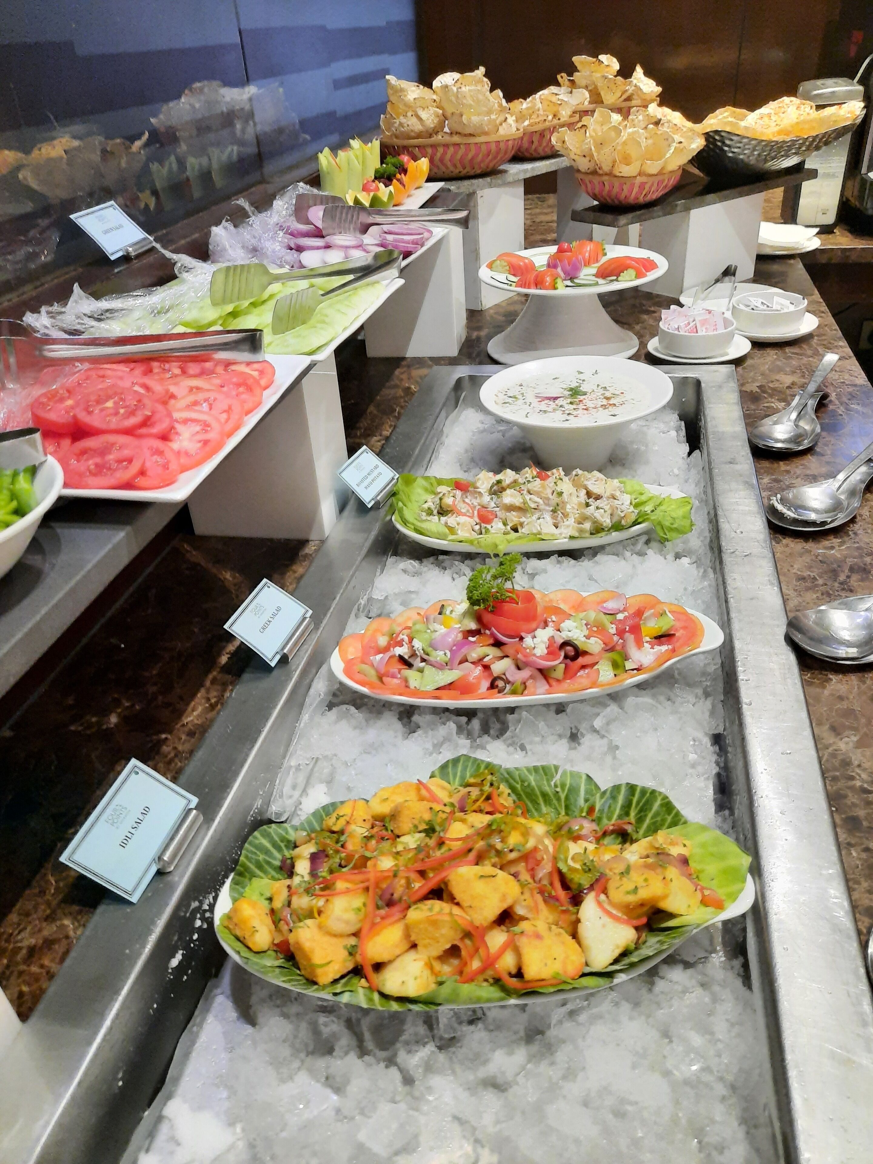 A buffet with various salads and dishes displayed on trays.
