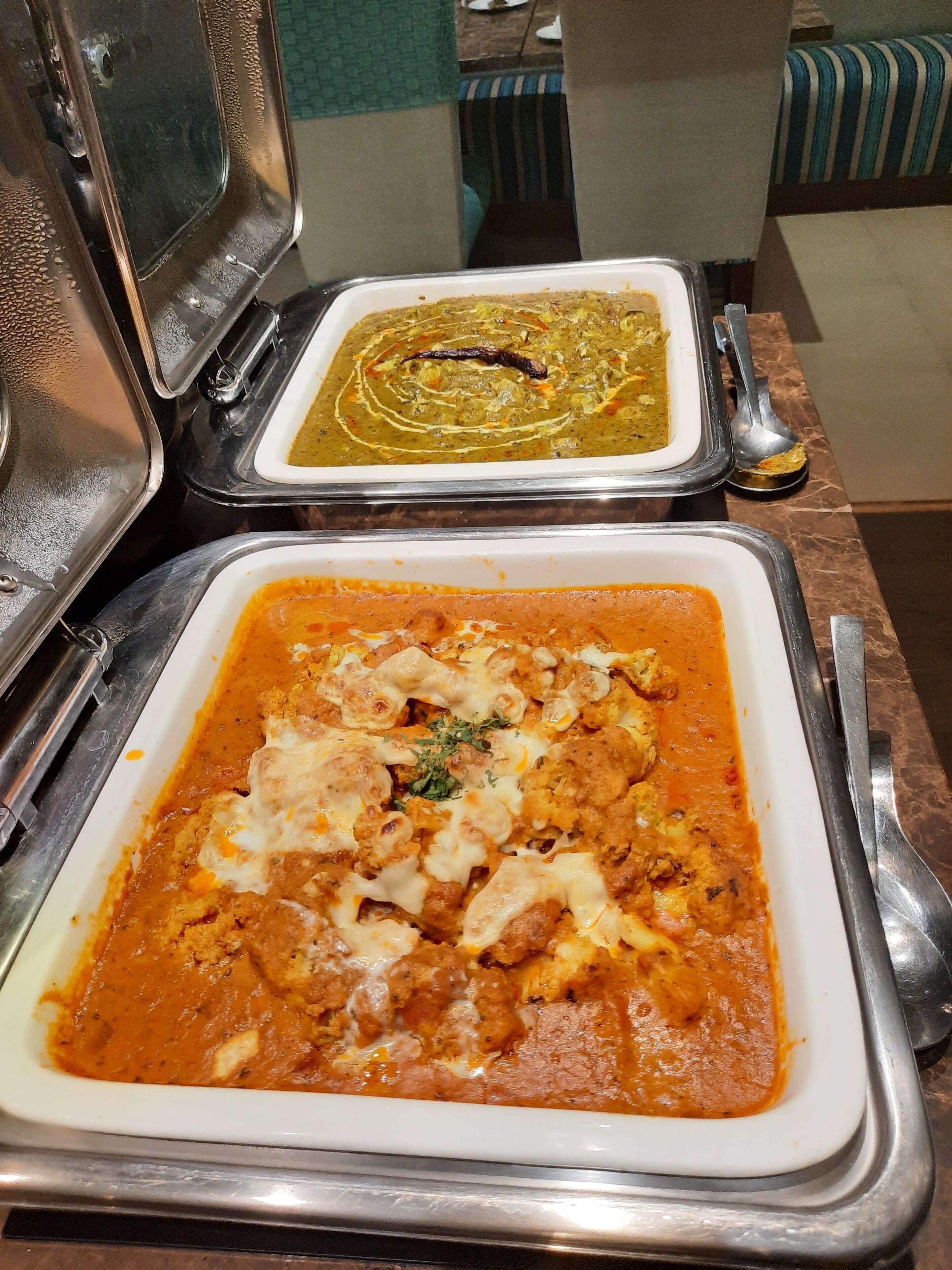 Un bufé con diversos platos, incluyendo un curry y un guiso de carne con queso.