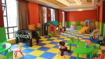 Kids can play and have fun in this vibrant play area with a foosball table, playhouse, slide, and toy car.