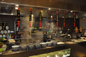 Una cocina con diversos utensilios de cocina, ollas y botellas. Hay decoraciones colgantes y una encimera con cuencos y platos.