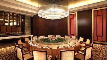 A round table with chairs, a chandelier, and a buffet in a hotel room.