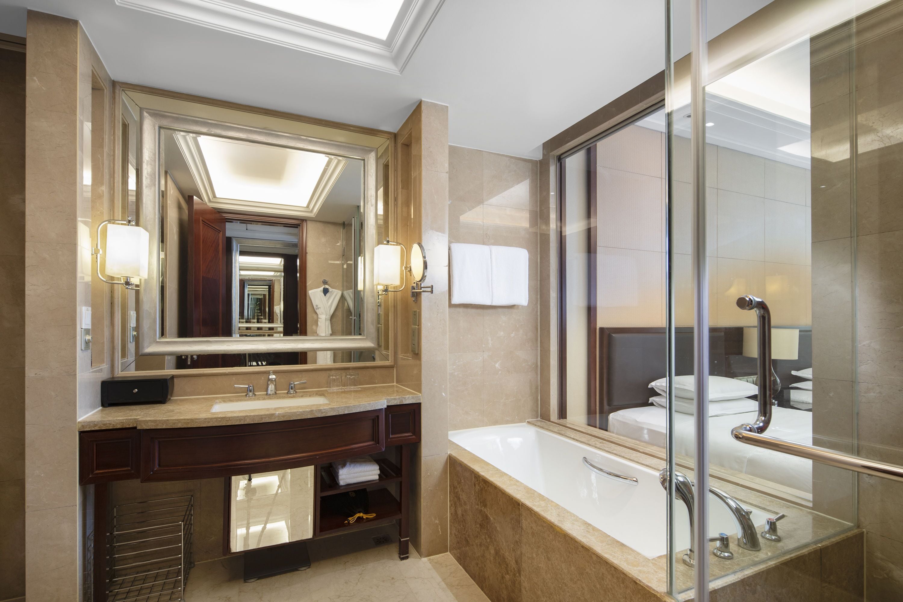 Une salle de bain moderne dotée d’un grand miroir, de deux vasques, d’une baignoire et d’une cabine de douche en verre.