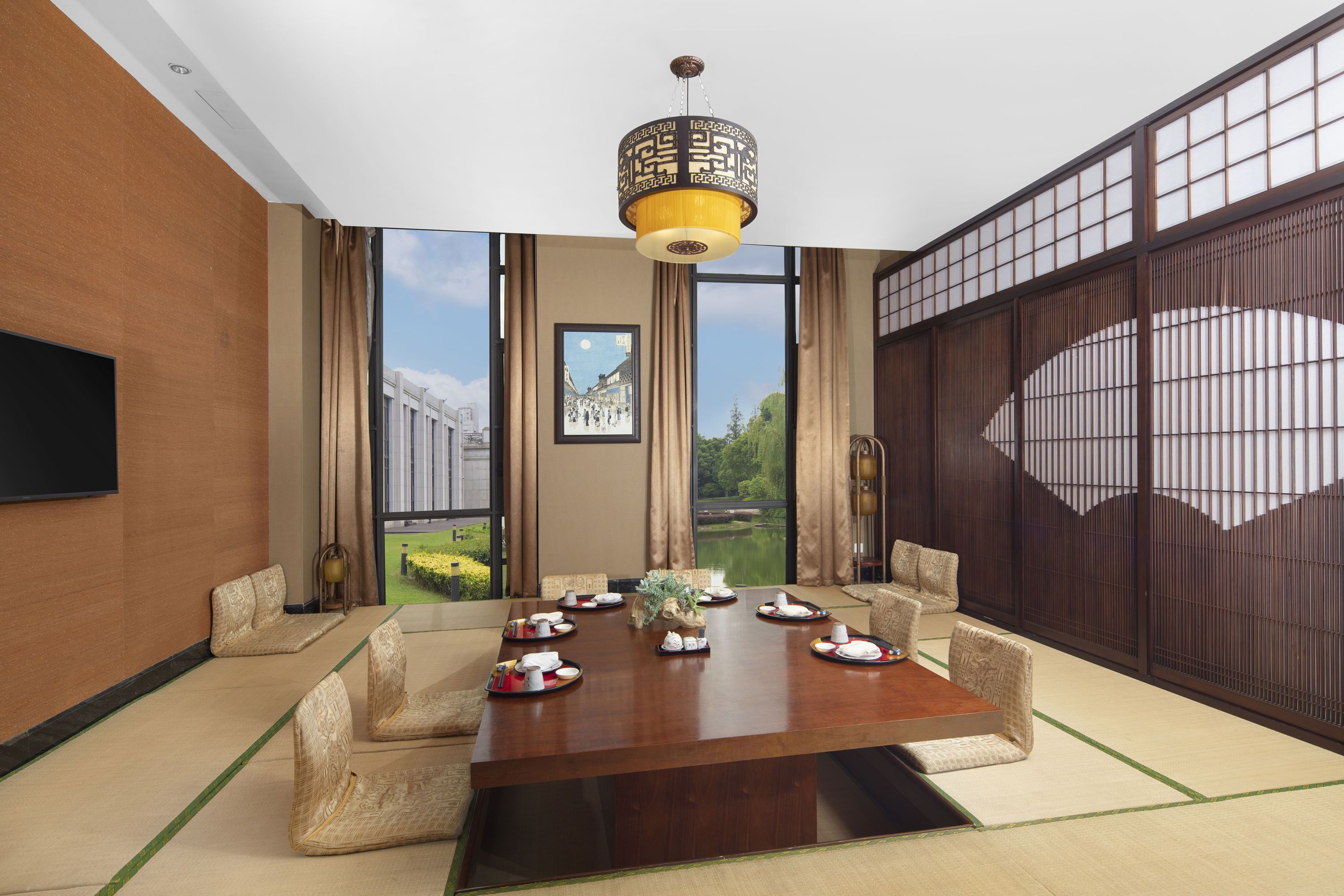 Une pièce de style japonais traditionnel, avec un sol recouvert de tatamis, une petite table en bois préparée pour le repas et un grand paravent shoji.