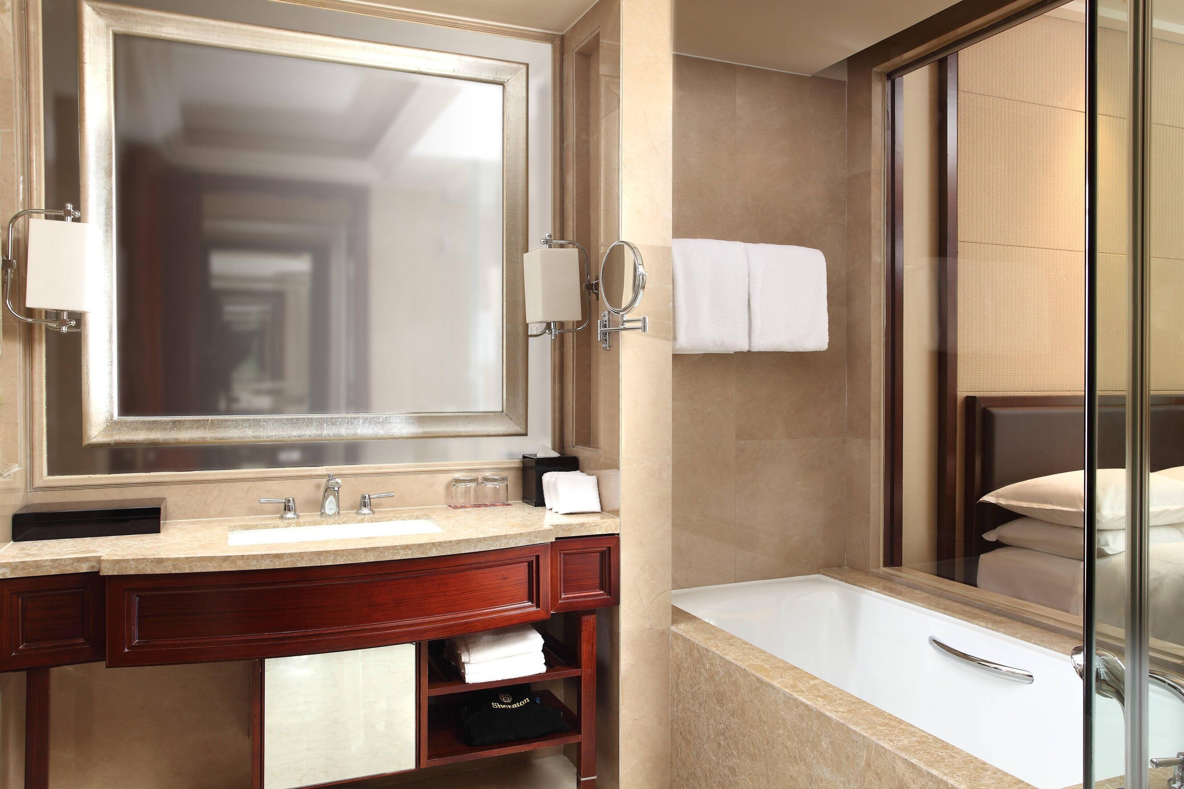 A modern bathroom with a large mirror, a sink, a bathtub, and a glass shower enclosure.