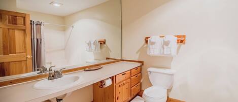Ein Badezimmer mit Holzwaschtisch, Waschbecken, Spiegel, Toilette und Handtuchhalter.
