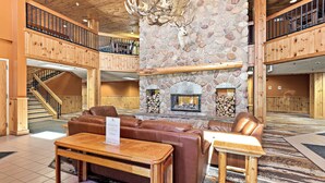 A spacious lobby with a stone fireplace, leather seating, and a wooden staircase. - Superior Shores  (Two Harbors)