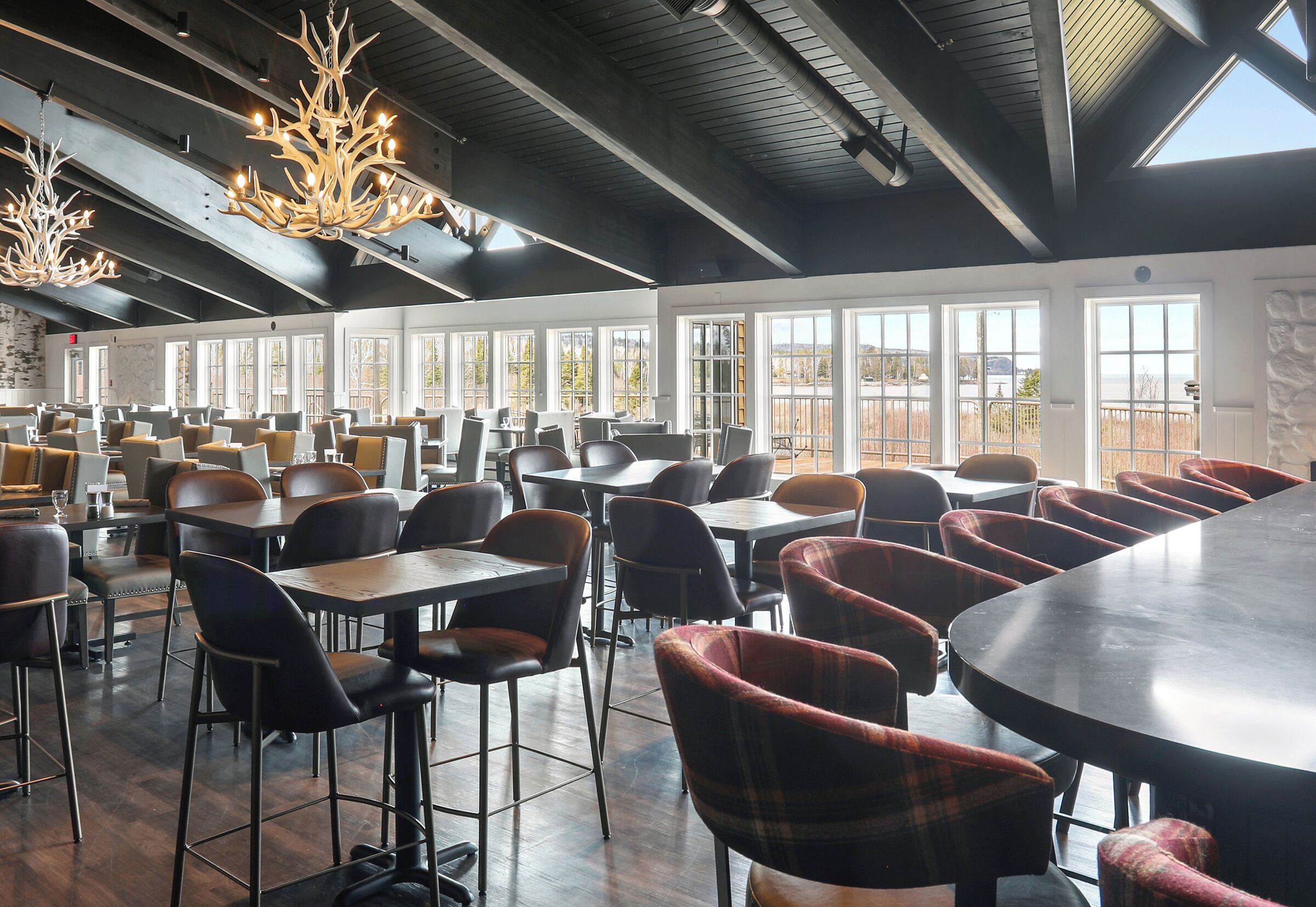 Een ruime eethoek met hoge plafonds, grote ramen en moderne verlichting.