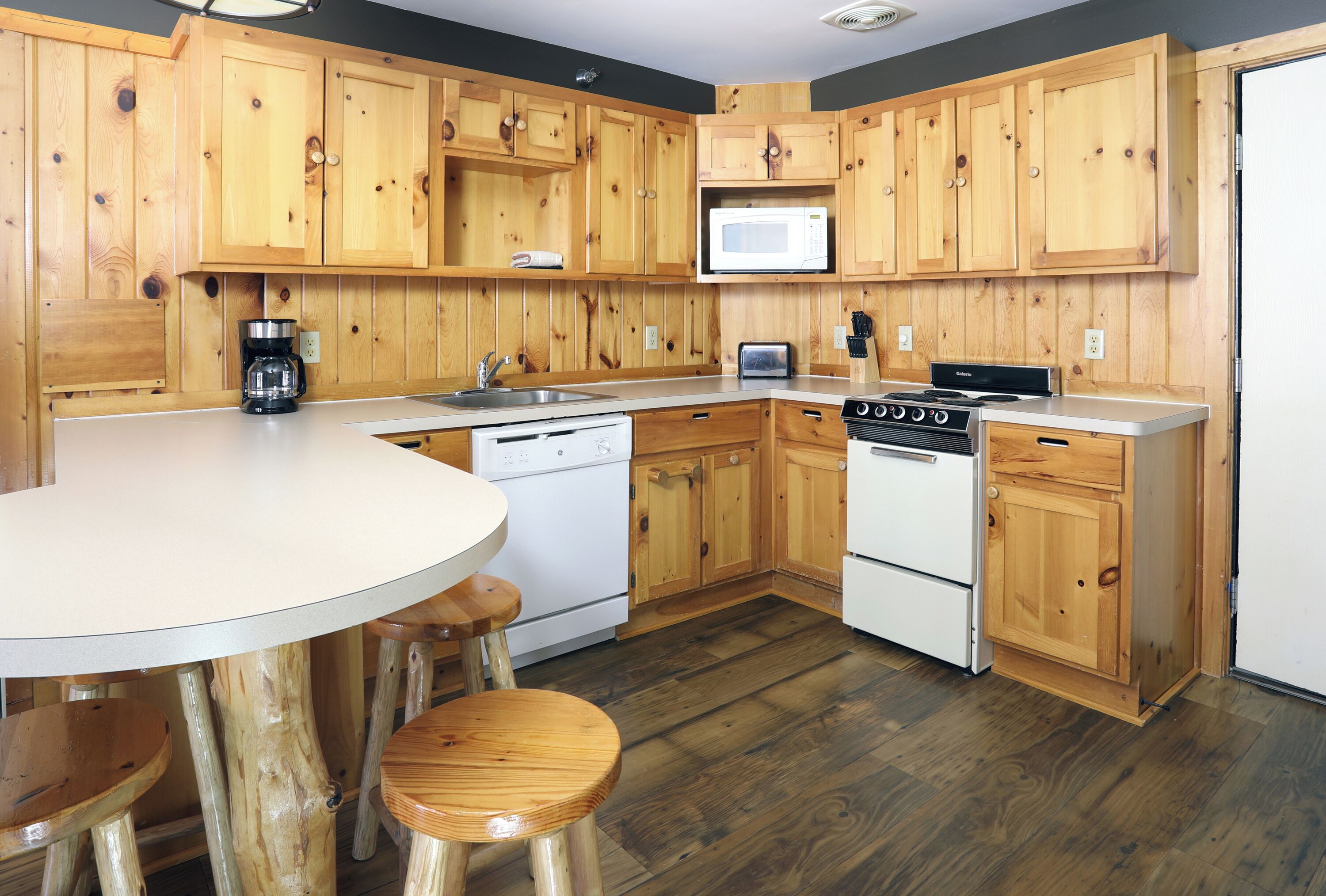 A kitchen with wooden cabinets, a microwave, a toaster, and a stove.