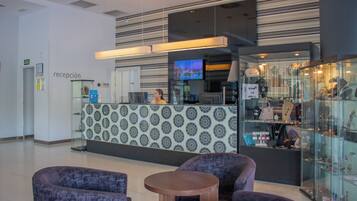 A reception area with patterned wallpaper, a TV screen, and a glass display case with items.