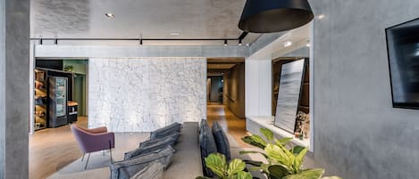 Een modern interieur met een stenen muur, een zithoek en een grote plant.
