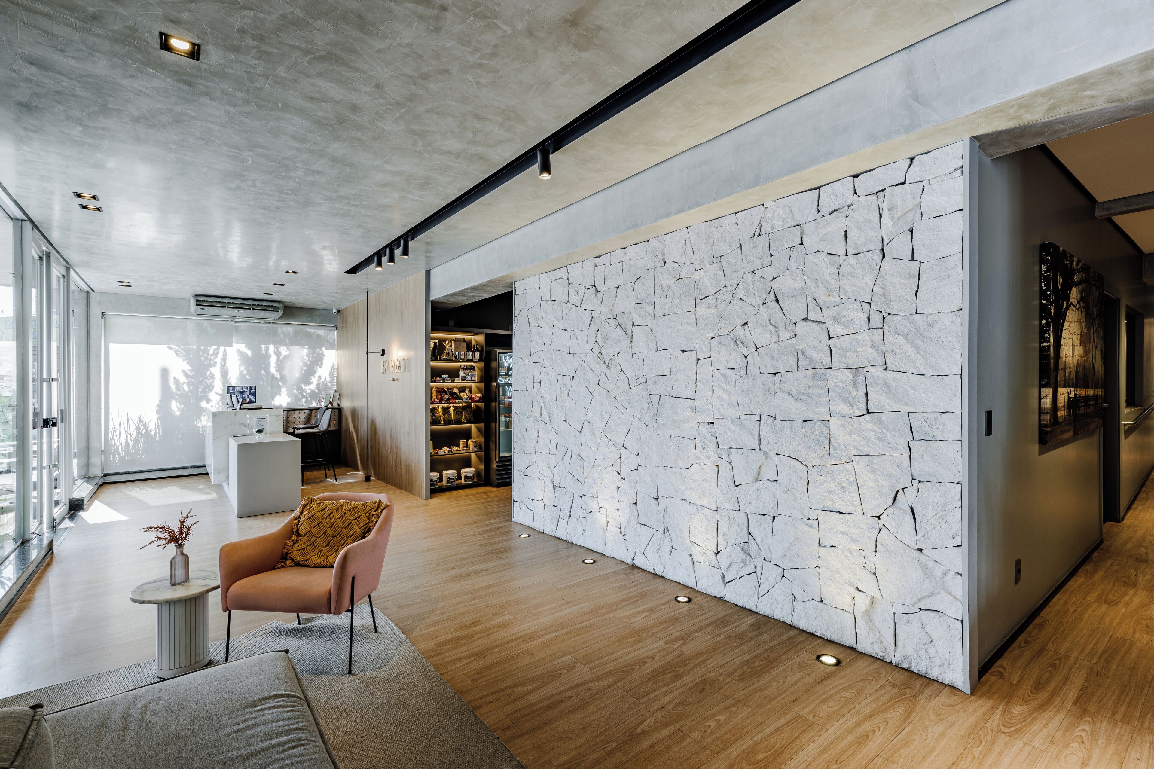 Ein modernes Interieur mit Steinwand, Holzboden und einer Sitzecke mit Sofa und Sesseln.