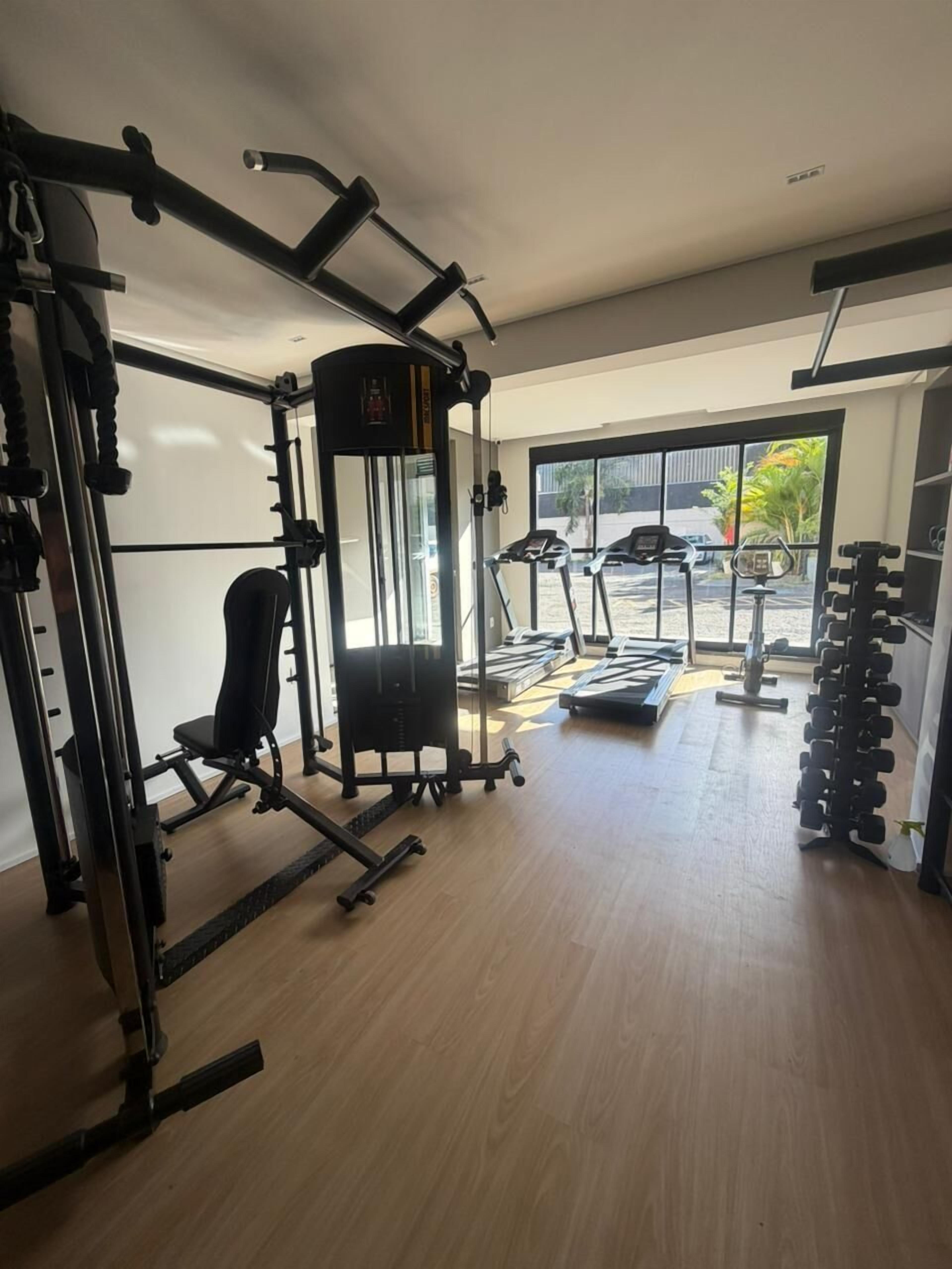 Un gimnasio con equipo de ejercicio, una cinta de correr y un estante con mancuernas.