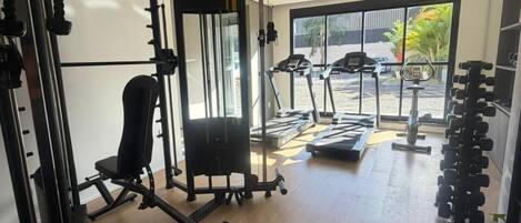 Un gimnasio con equipo de ejercicio, una cinta de correr y un estante con mancuernas.