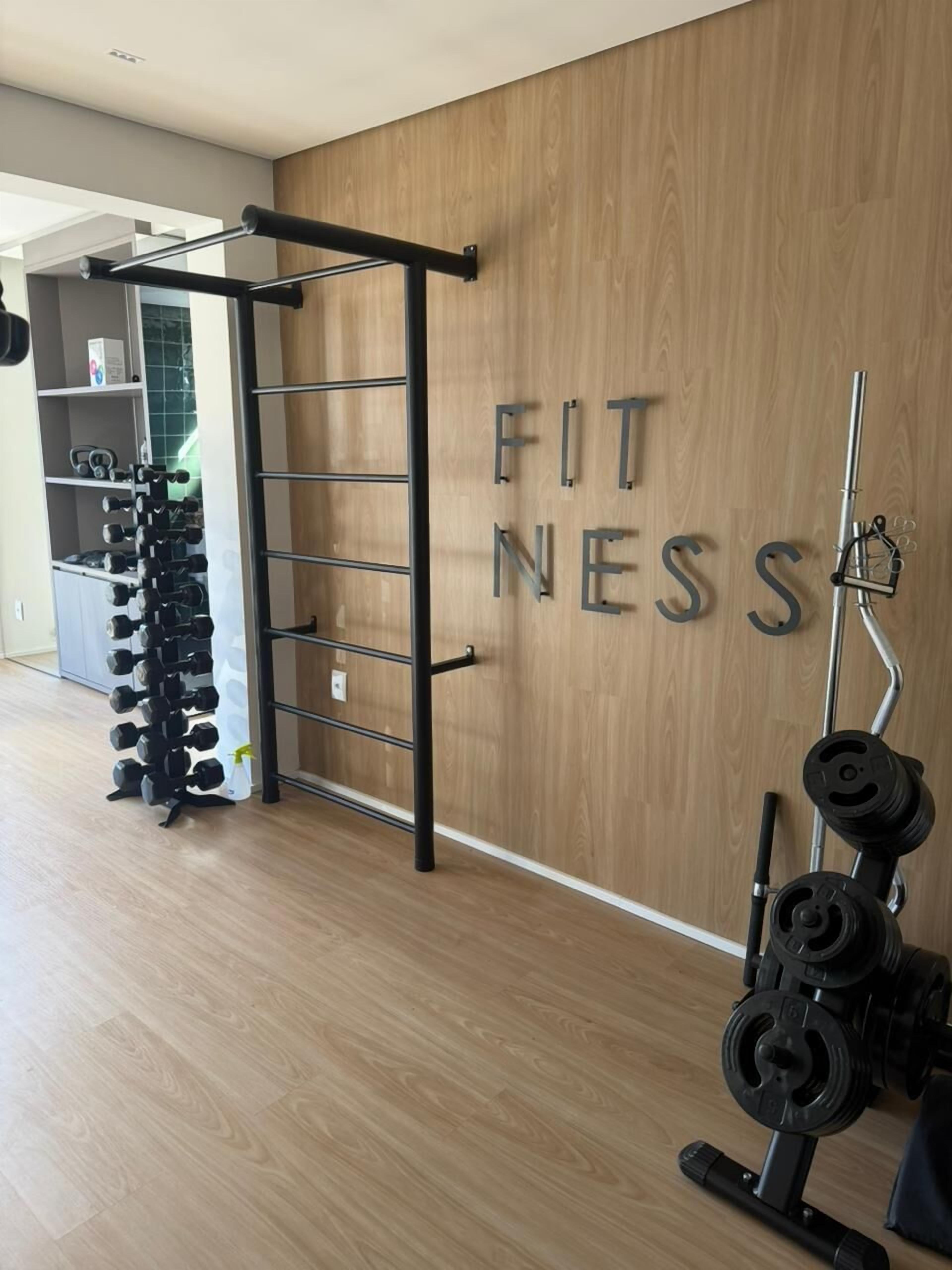 A gym with a pull-up bar, weight rack, and a wall with 'FITNESS' letters.