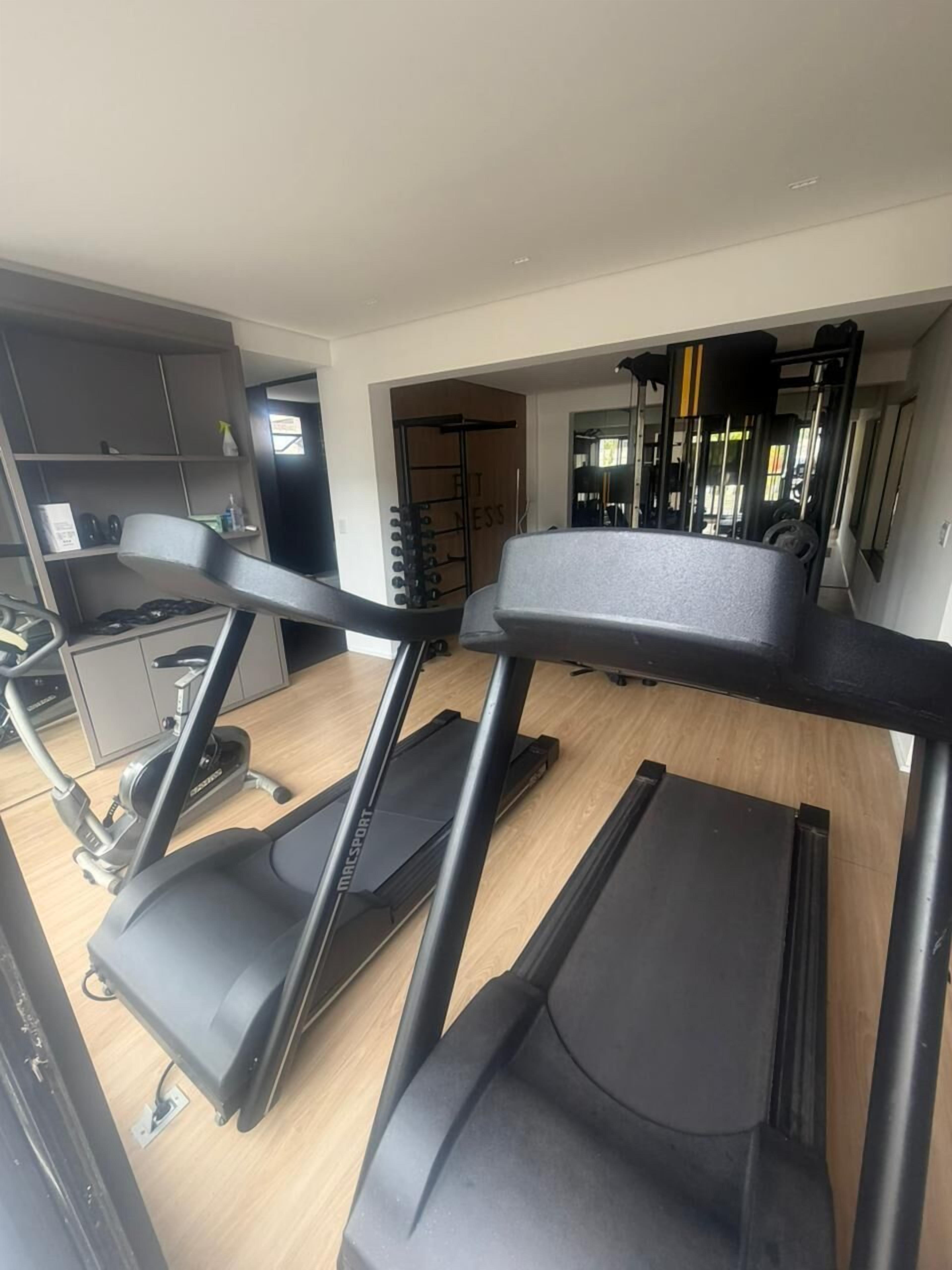 Un gimnasio en casa con cintas de correr, una barra de dominadas y un banco de pesas.
