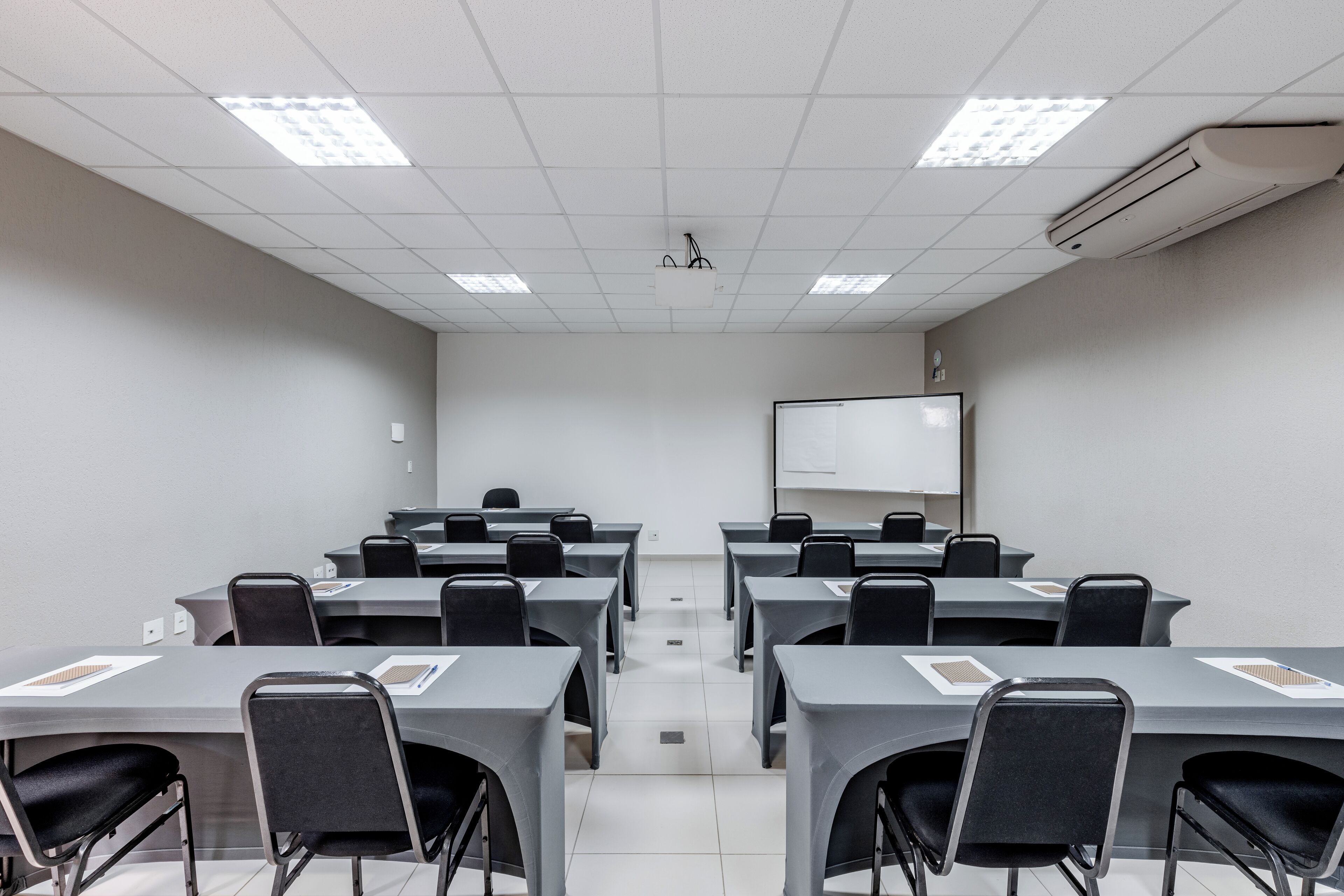A conference room with tables and chairs, a projector, and a whiteboard.