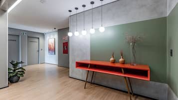 Un interior moderno con piso de madera, una consola roja y una pared decorativa verde.