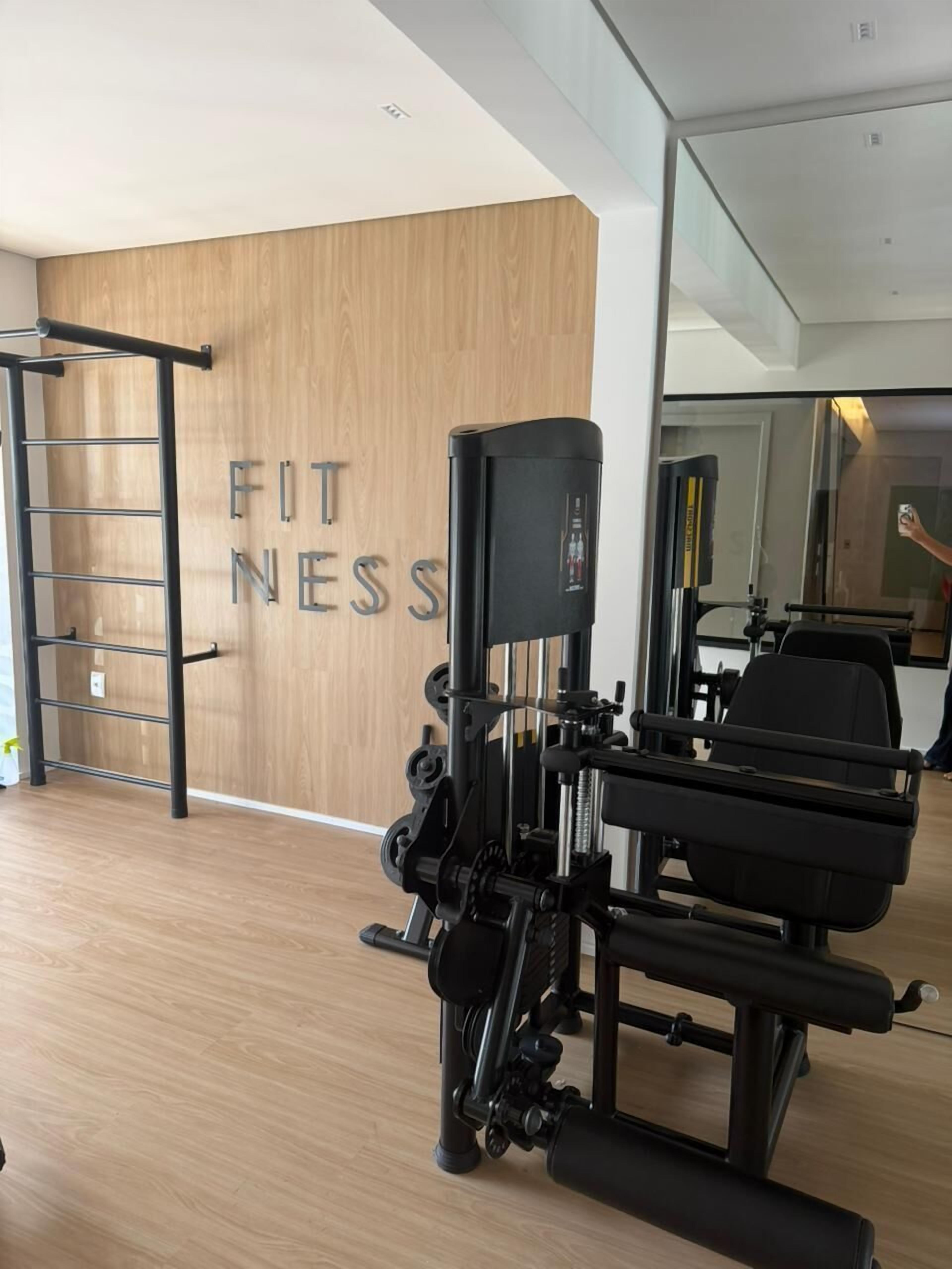 Une salle de sport avec un mur en bois, une barre de traction et une machine de musculation.