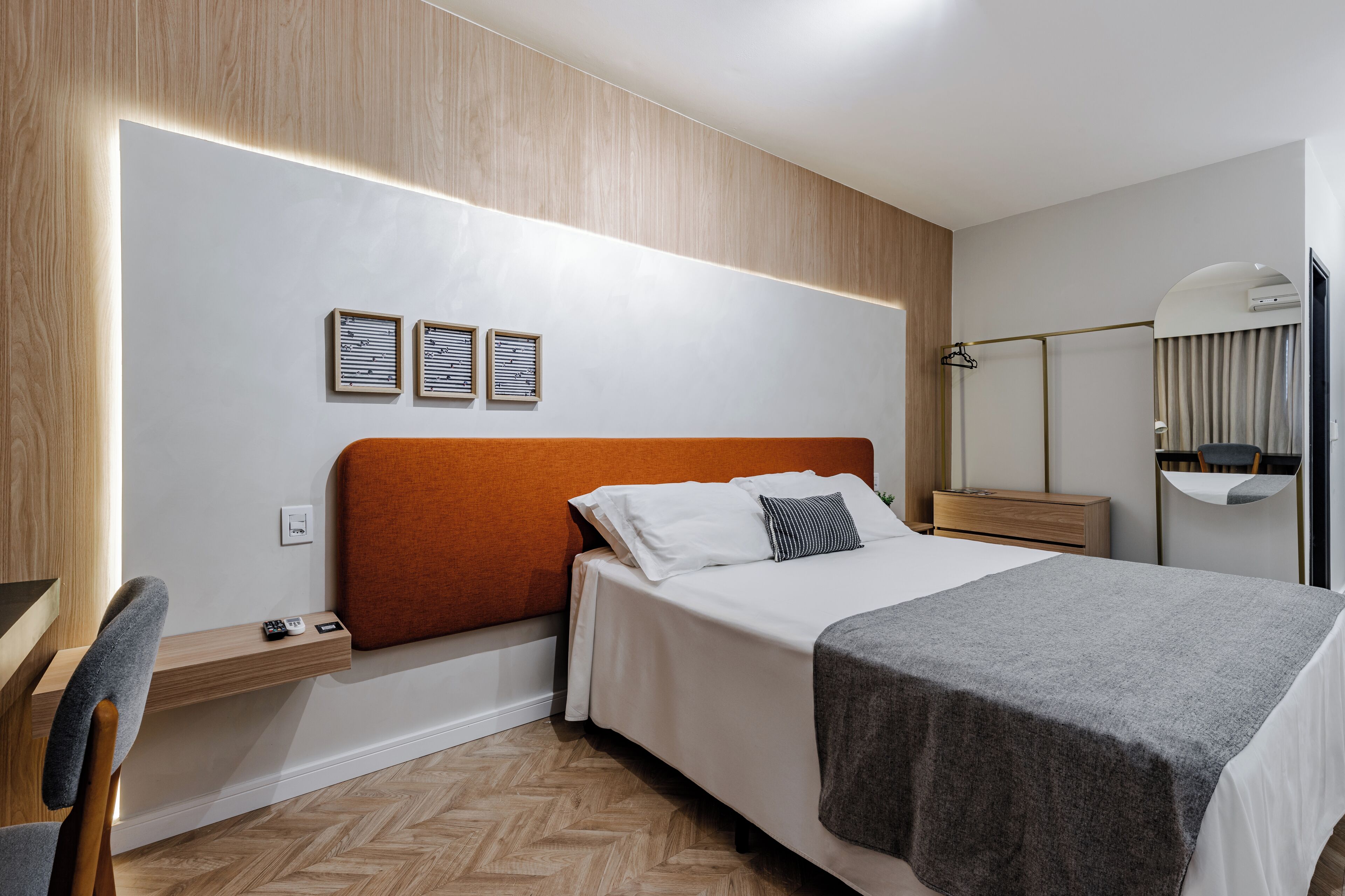 Een moderne hotelkamer met een groot bed, een nachtkastje, een stoel en een spiegel.