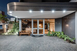A modern building with a curved entrance, a wooden bench outside, and a sign that reads "Parati." - Hotel Parati Minas (Uberlandia)