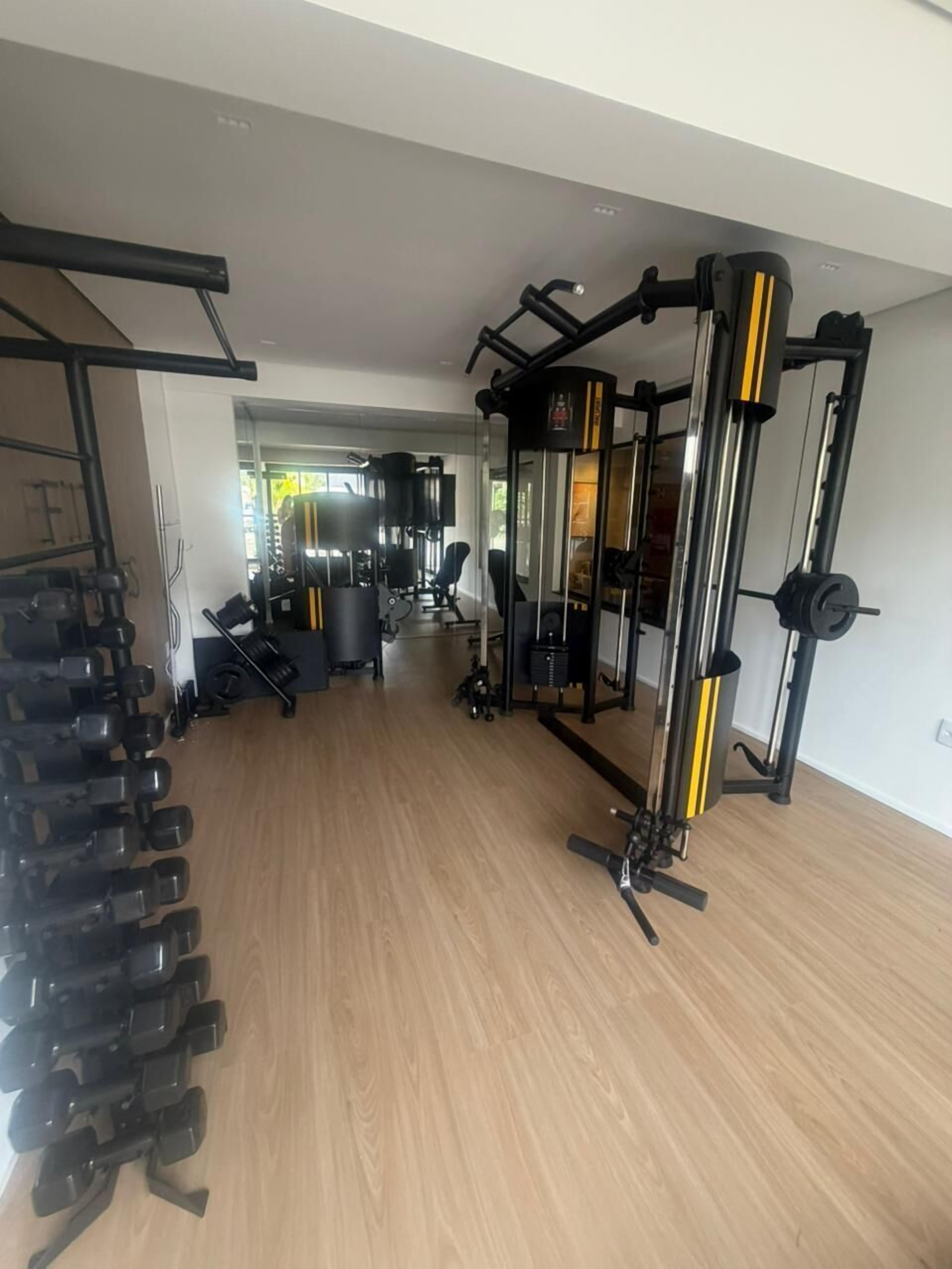 A gym with exercise equipment, a rack of dumbbells, and a mirror.