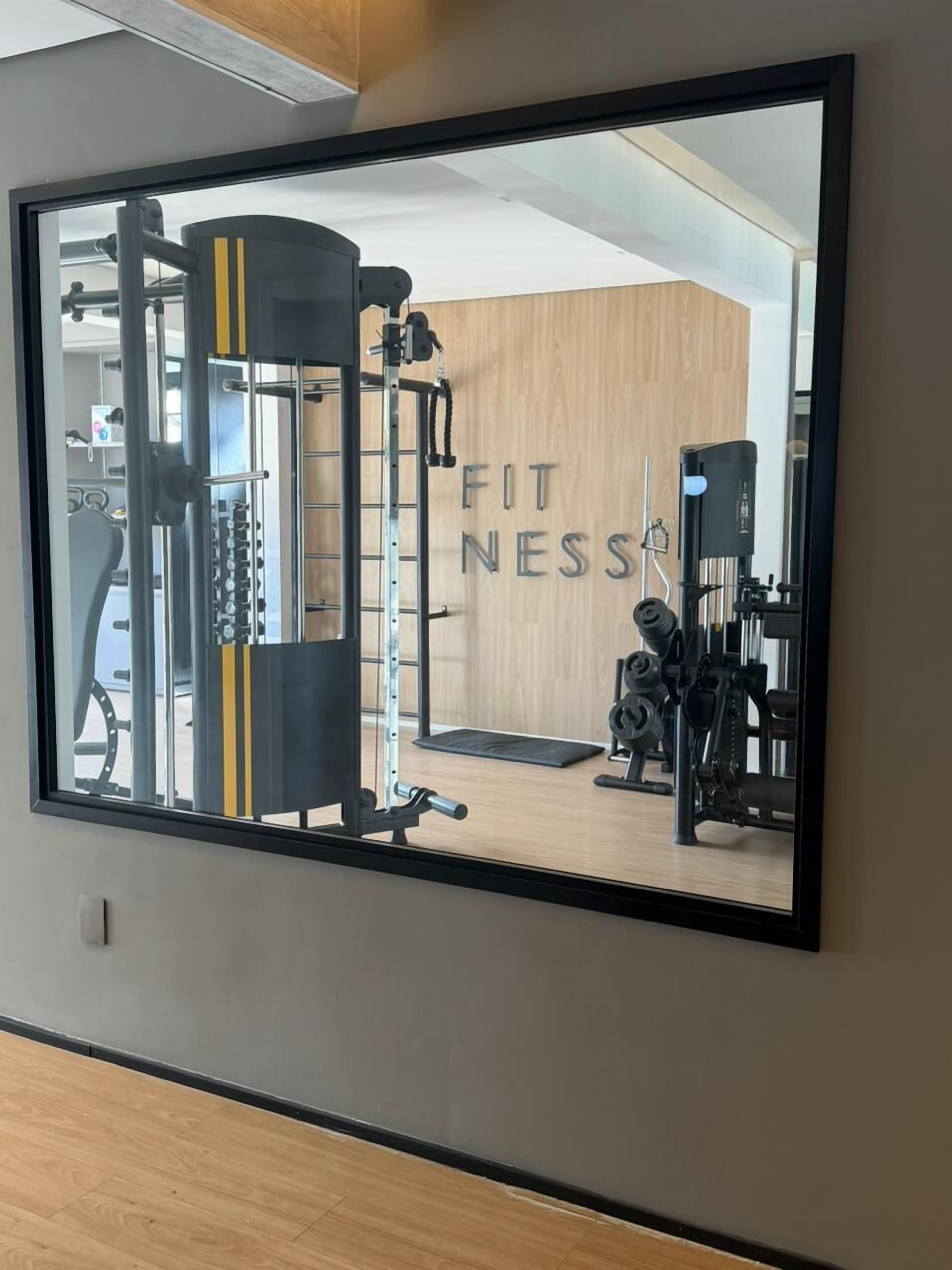 Un gimnasio con equipo de ejercicio, un espejo y un cartel que dice 'FITNESS'.