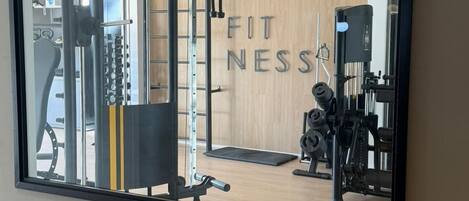 Un gimnasio con equipo de ejercicio, un espejo y un cartel que dice 'FITNESS'.