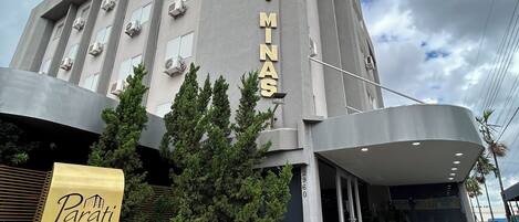 A hotel named 'Hotel Parati Minas' with a modern design, featuring a prominent entrance and air conditioning units on the facade.