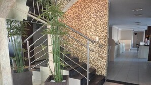 A modern staircase with metal railings and a potted plant at the bottom. - Guarany Hotel Express (João Pessoa)