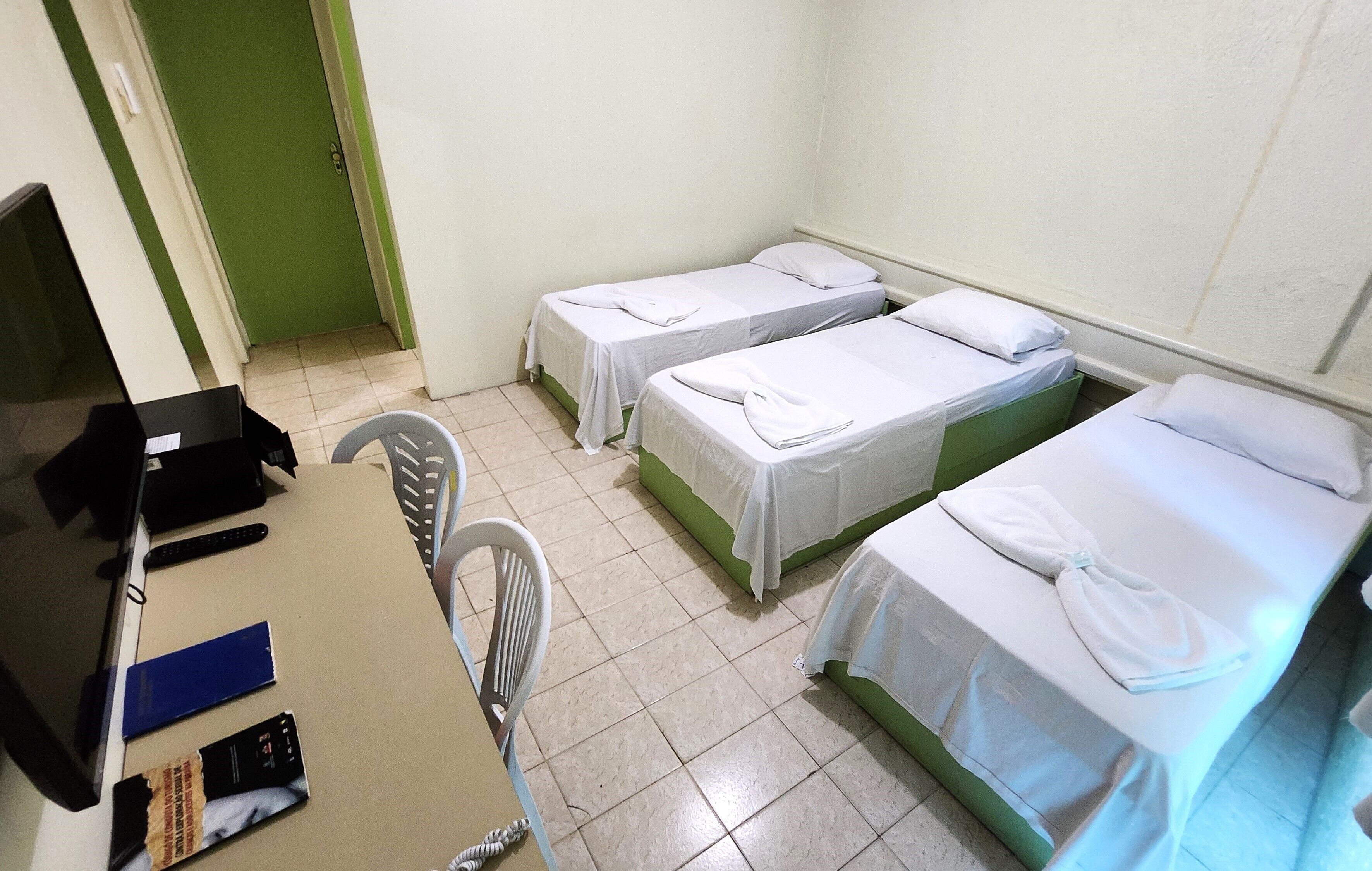 A room with two single beds, a desk with a computer, and a chair.