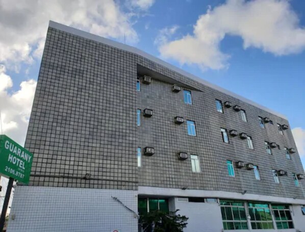 A multi-story hotel with a grid-patterned facade, air conditioning units, and a sign for the GUARANY HOTEL. - Guarany Hotel Express (João Pessoa)