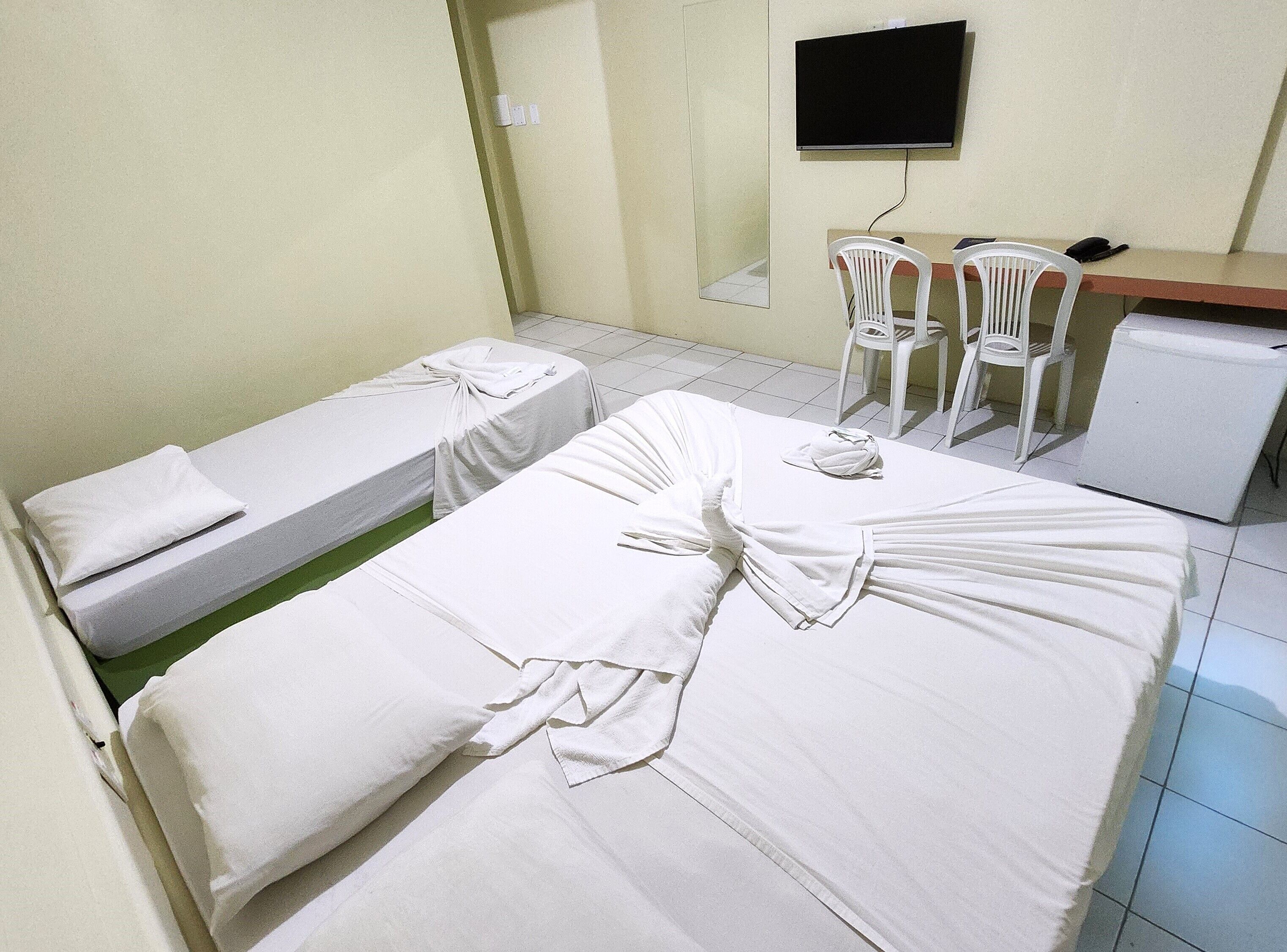 Een hotelkamer met twee bedden, een bureau, een stoel en een televisie.