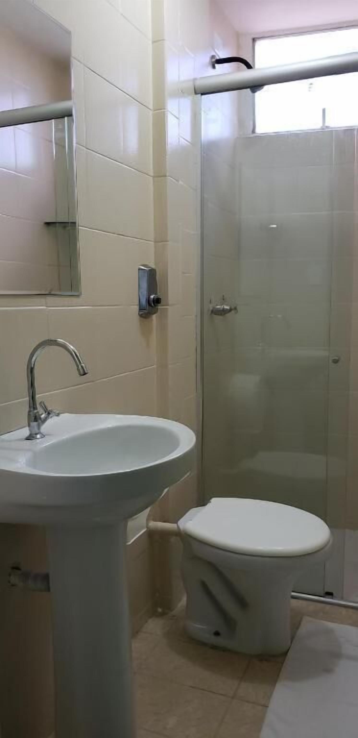A bathroom with a pedestal sink, a toilet, and a glass shower enclosure.