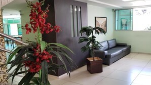 A modern lobby with a staircase, a dark leather sofa, and potted plants. - Guarany Hotel Express (João Pessoa)