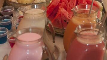 Un bufé con diversas frutas, como sandía y piña, y varias jarras de bebidas.