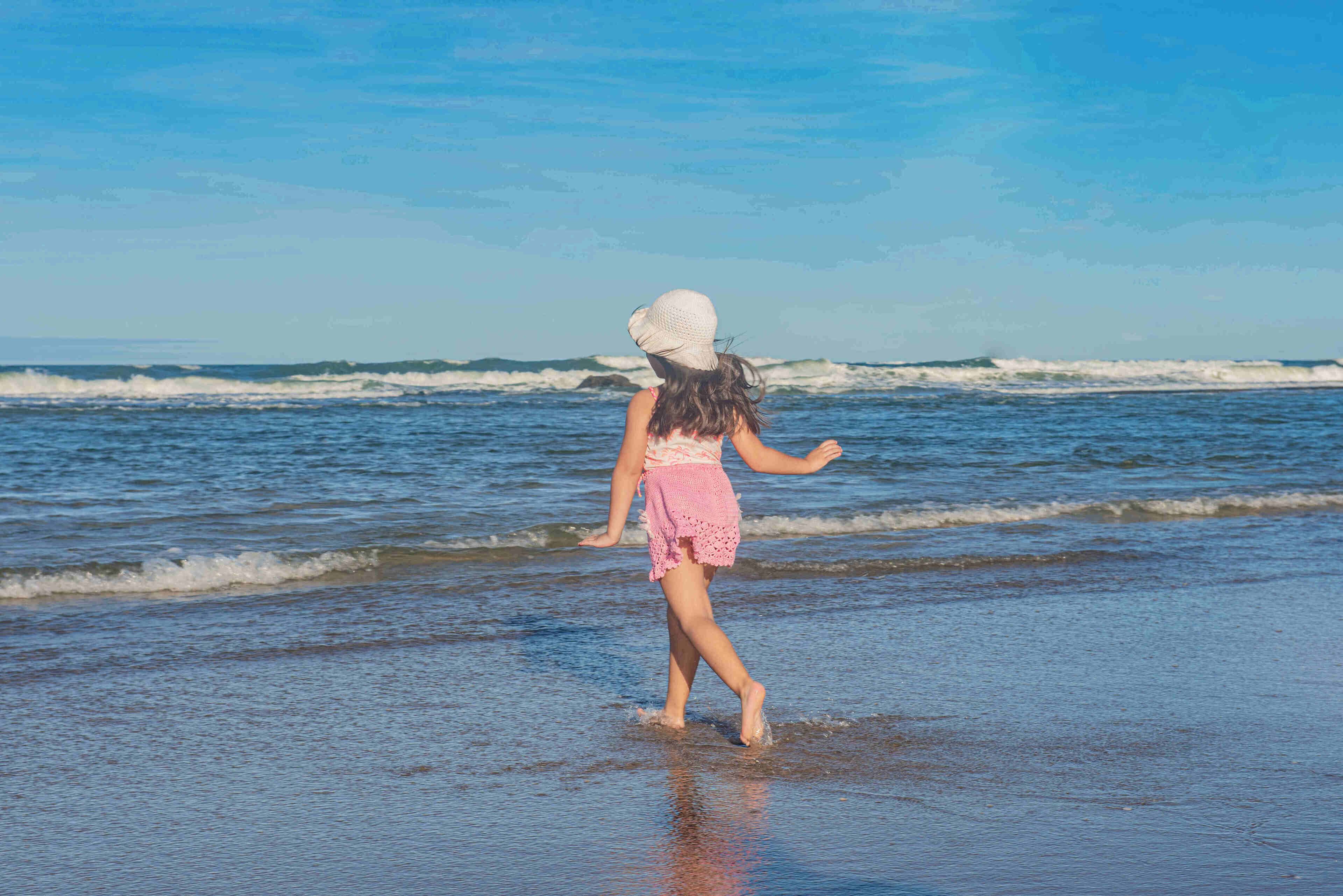 A person walking on a beach with waves in the background.