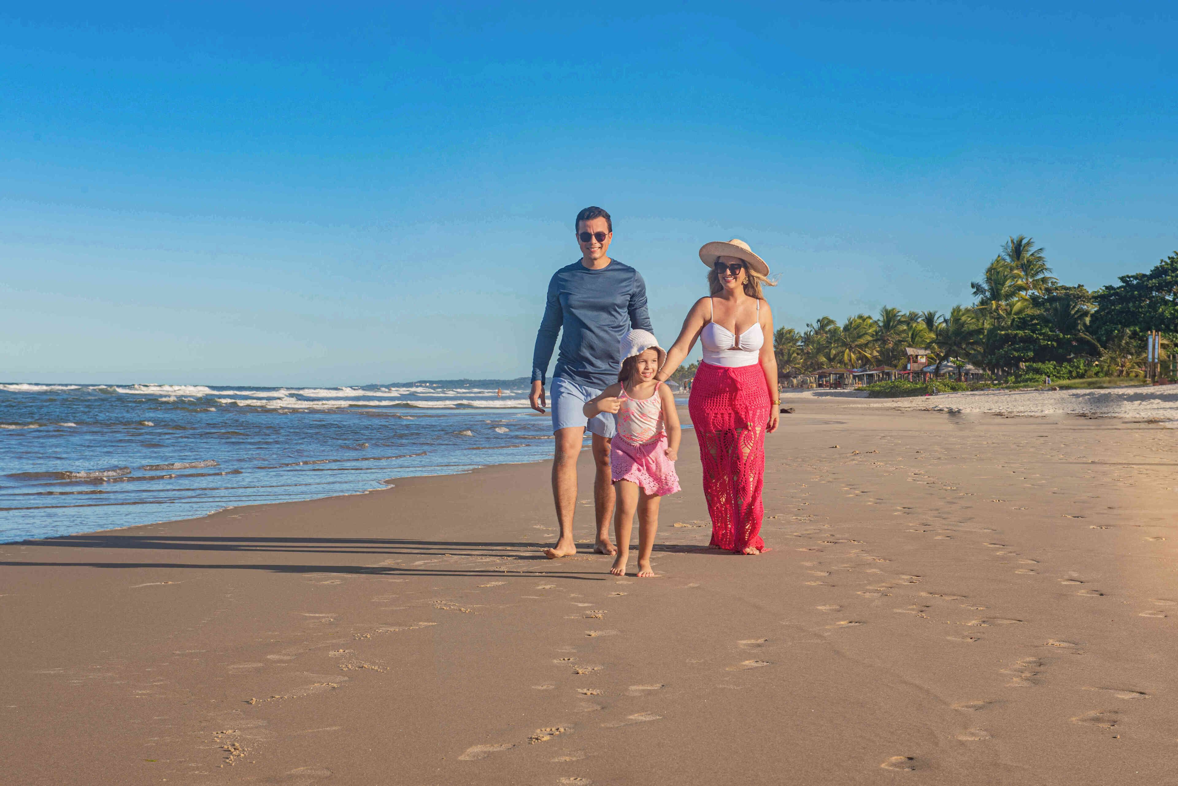 A beach with footprints, palm trees, and a clear sky.