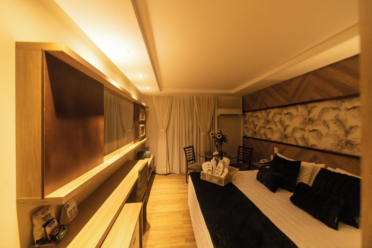 A hotel room with a bed, a TV, a desk, and a chair.