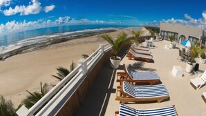 A beachside resort with lounge chairs and umbrellas, a pool area, and a view of the ocean. - Opaba Praia Hotel (Ilhéus)