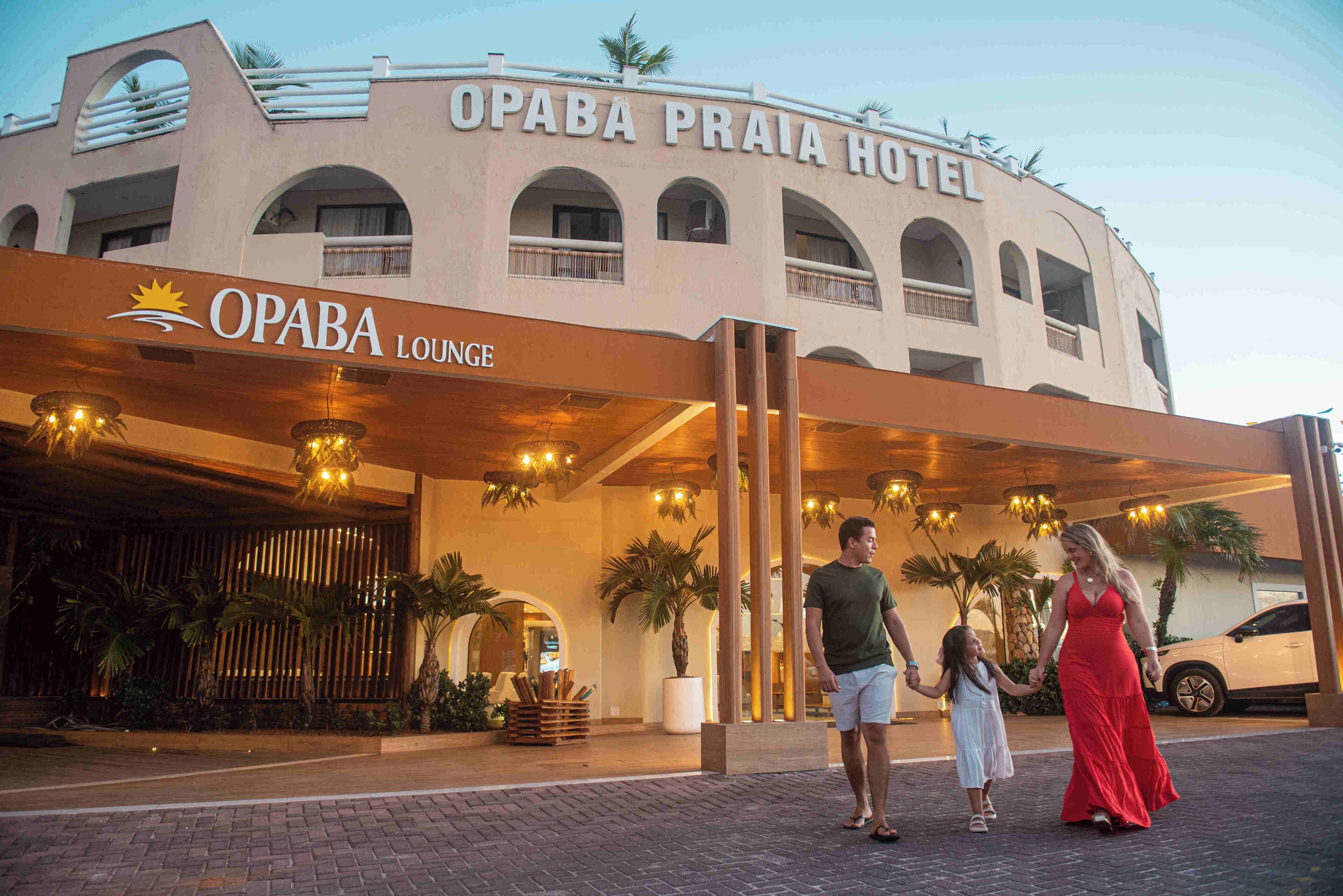 Hotel Opaba Praia, con una entrada destacada, un área de descanso y palmeras.
