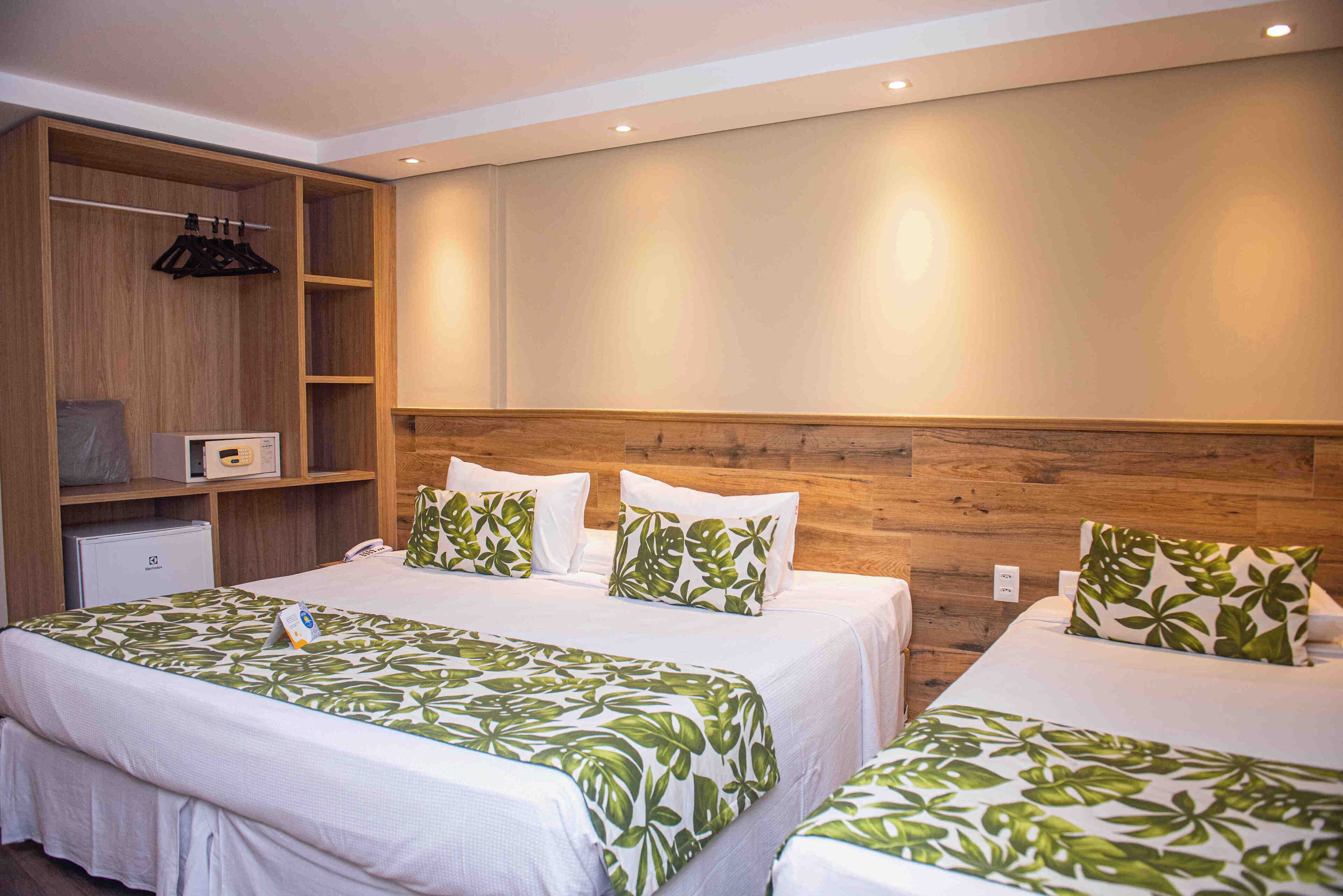 Une chambre d’hôtel avec deux lits, une armoire en bois et un petit bureau avec un téléphone.